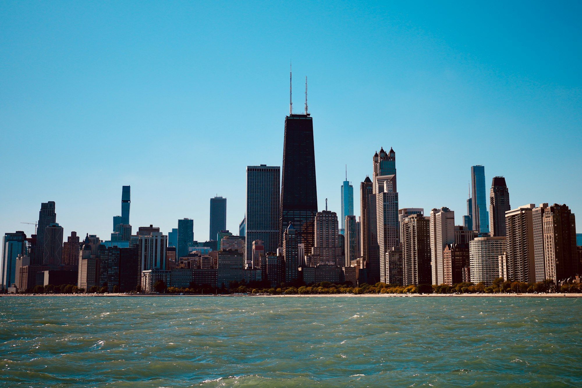 The Chicago skyline from Lake Michigan on a clear day, with a dark twin-antenna tower at its centre